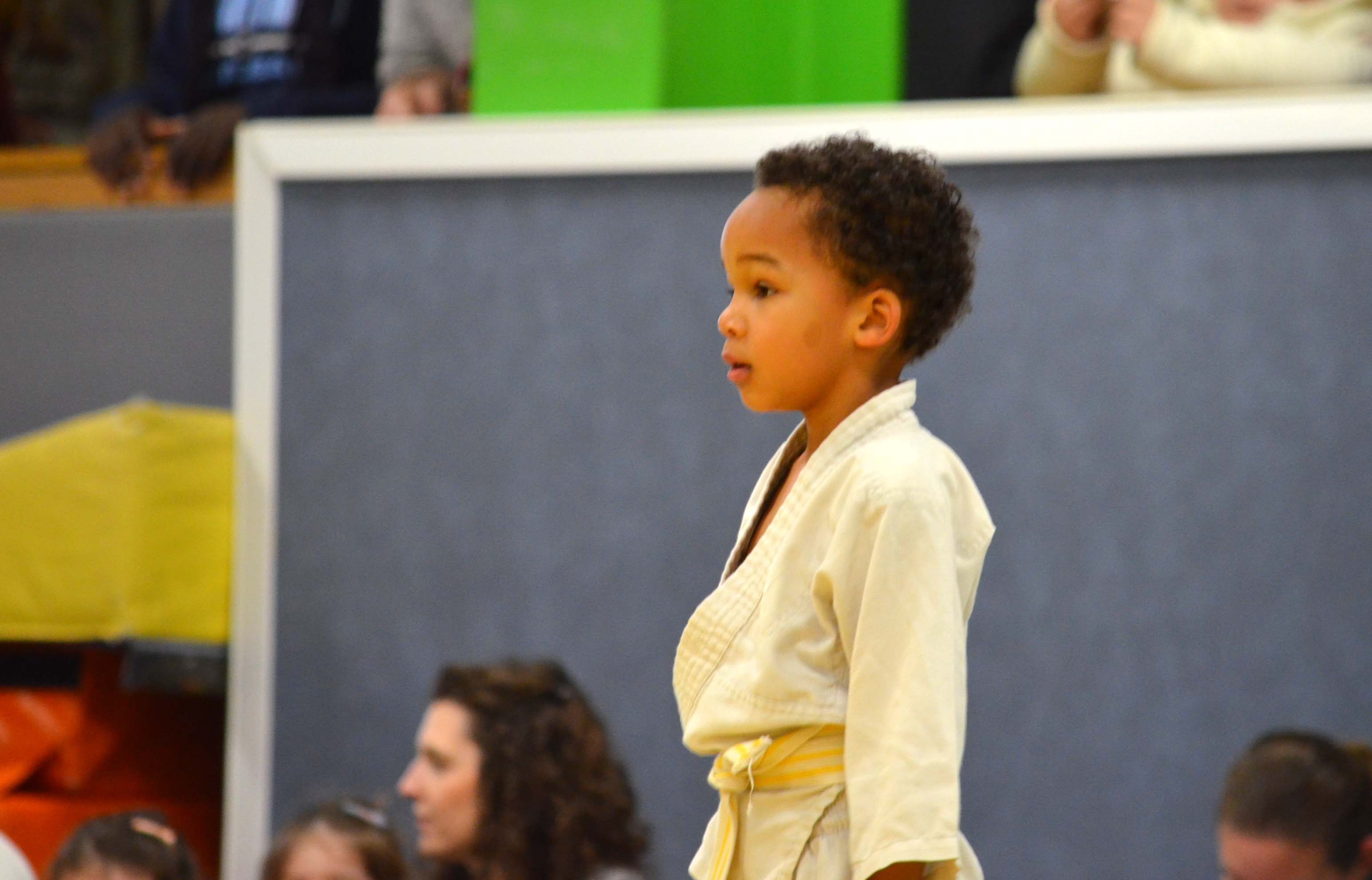 Jeune enfant en judogi de profil, concentré pendant un cours de judo